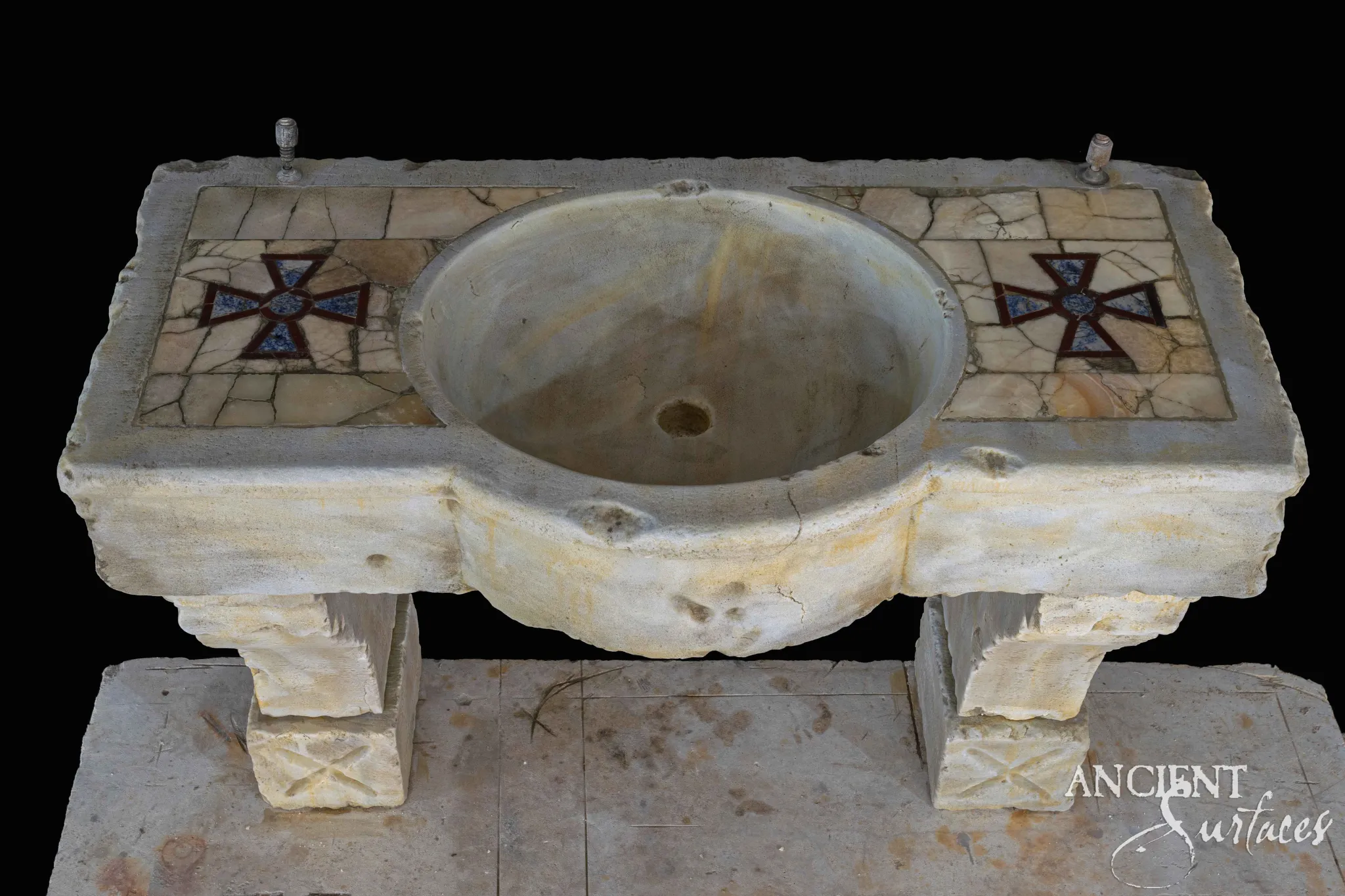 Reclaimed limestone sink with a round basin flanked by cross-motif pietra-dura mosaic inlay panels