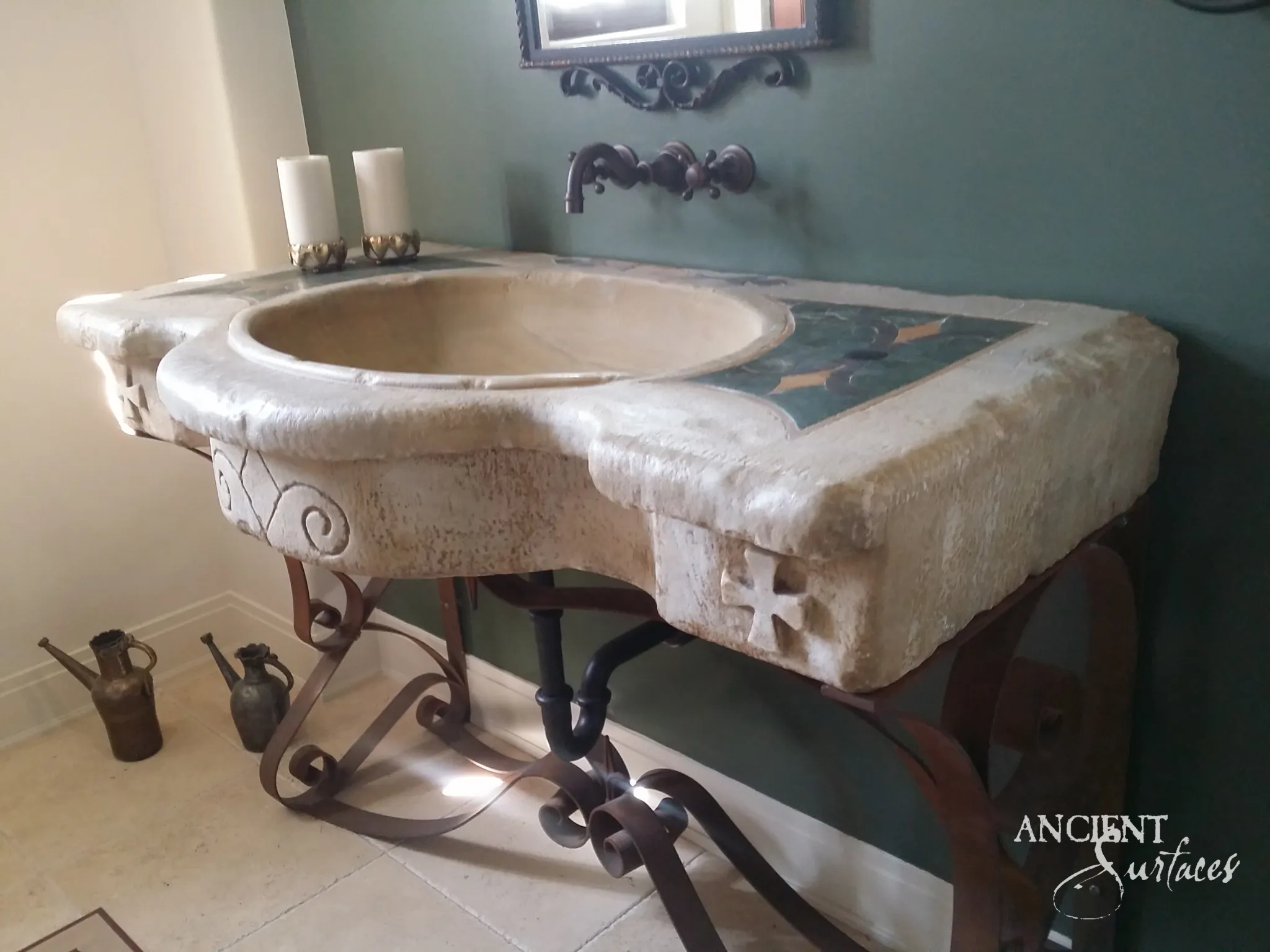 Hand-carved reclaimed limestone sink with a shaped basin and carved apron set on a wrought-iron scroll base