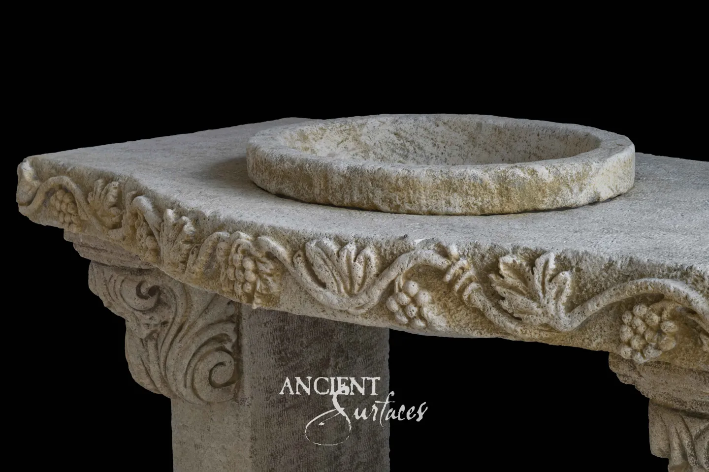 Round reclaimed limestone basin on a slab carved with a grapevine border above a scrolled capital